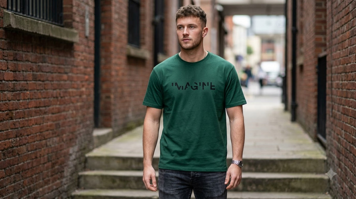 Model wearing AuraReiment's dark green Imagine graphic T-shirt in a brick alley.